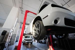 Muscle car with open hood at service repair station in lift. photo