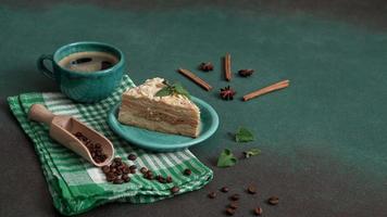 Delicious Napoleon Cake with cream on a turquoise plate decorated with a sprig of mint on a Green Background. A cup of hot coffee, cinnamon stick, badyan, coffee beans on a green background video