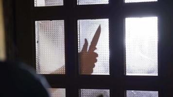 fêmea abuso.violência e assédio contra mulheres. mulher receoso do masculino silhueta segurando uma faca às lar. video