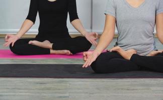 mujer haciendo yoga meditando ejercicio en loto posición con mudra durante yoga clase. trabajando fuera vistiendo negro camisa y blanco pantalones. cuidado de la salud concepto. foto