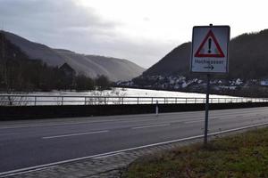 flood sign at the road next to the flood photo