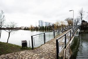 Pedestrian bridge of lake promenade with glass building multistorey residental house on background. photo