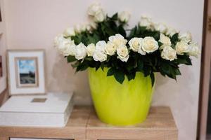 White roses flowers bouquet in green pot at home. photo