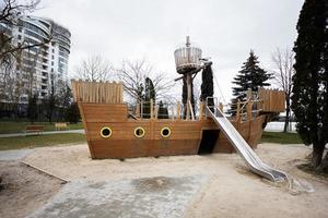 de madera Embarcacion y diapositiva en niños patio de recreo en ciudad. foto