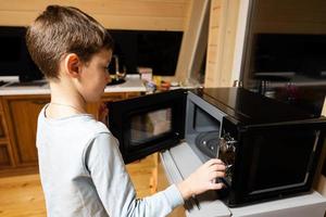 Boy uses the microwave oven in the kitchen. photo