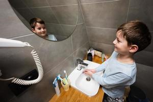 Boy washes hands in the sink at bathroom. photo