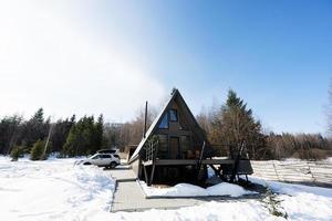 Wooden triangle country tiny cabin house with hot tub spa and suv car with roof rack in mountains. Soul weekends. photo