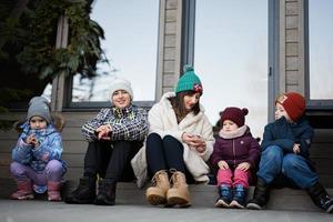 Mother with four children sit on terrace off grid tiny house in the mountains. photo