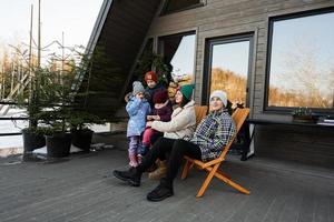 Mother with four children sit on terrace off grid tiny house in the mountains. photo