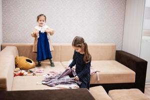 dos hermanas están eligiendo ropa del armario en casa en el sofá. foto