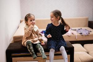 Two sisters sit on the sofa and tell and share girlish secrets with each other. photo