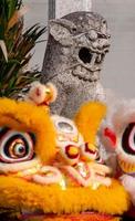 Old lion statue with front lion dance in front of temple photo