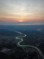 Aerial view river across plantation during sunset photo