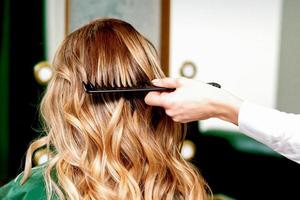 Hairdresser combing wavy hair of woman photo