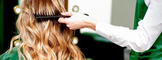 Hairdresser combing wavy hair of woman photo