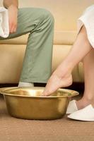 Woman is dipping feet in bowl photo