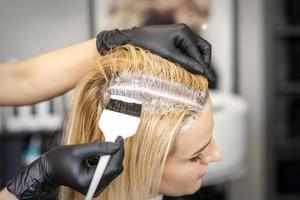 Hairdresser dyeing blonde hair roots photo