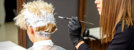 Female hairdresser dyeing short hair photo