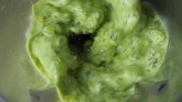 elevado Visão do verde chá dentro liquidificador completamente esmagamento gelo. video