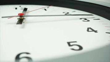 Nahansicht von ein Weiß Uhr mit schwarz Zahlen und ein Minute Hand zeigen zwischen vier und fünf. video