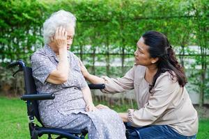 Caregiver help Asian elderly woman disability patient sitting on wheelchair in park, medical concept. photo