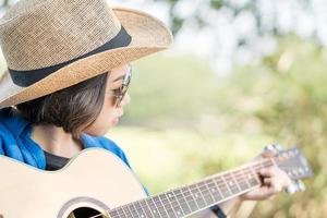Close up woman wear hat and playing guitar photo