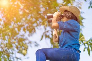 Close up Woman wear hat and hold binocular in grass field photo