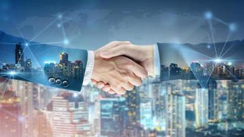 Successful businessman handshake startup new project at city night background, Double exposure of professional teamwork and network connection partnership concept, international business investment photo