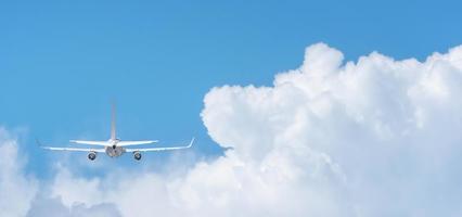 Commercial airplane flying above clouds on day light, Clear blue sky and fluffy soft white cloud with copy space, Travel vacation trip concept photo