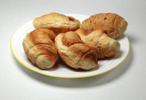 A plate of croissants with a yellow rim and a white rim photo
