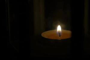 candlelight in lantern on black background of darkness at night. The burning of candles symbolizes worship, hope, encouragement, love, remembrance and relaxation. Soft and selective focus. photo