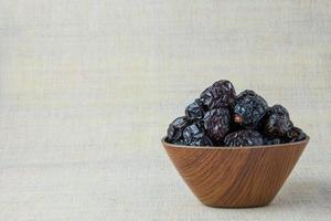 Delicious ajwa dates kurma nabi, or sweet dried dates on a plate, with some falling from the plate, as a meal for breaking the fast, ramadan kareem, empty space, copy space. photo