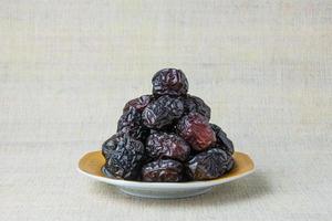 Delicious ajwa dates kurma nabi, or sweet dried dates on a plate, with some falling from the plate, as a meal for breaking the fast, ramadan kareem, empty space, copy space. photo