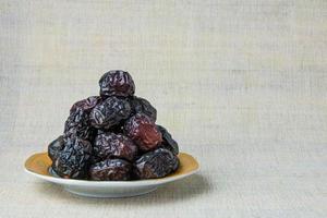 Delicious ajwa dates kurma nabi, or sweet dried dates on a plate, with some falling from the plate, as a meal for breaking the fast, ramadan kareem, empty space, copy space. photo