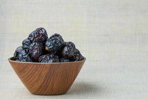 Delicious ajwa dates kurma nabi, or sweet dried dates on a plate, with some falling from the plate, as a meal for breaking the fast, ramadan kareem, empty space, copy space. photo