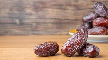 Delicious medjool dates or sweet dried dates on a plate, with some falling from the plate, as a meal for breaking the fast, ramadan kareem, empty space, copy space photo