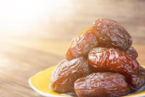 Delicious medjool dates kurma or sweet dried dates on a plate, with some falling from the plate, as a meal for breaking the fast, ramadan kareem, empty space, copy space. photo