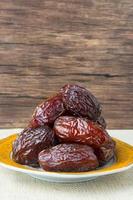 Delicious medjool dates kurma or sweet dried dates on a plate, with some falling from the plate, as a meal for breaking the fast, ramadan kareem, empty space, copy space. photo