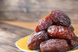 Delicious medjool dates or sweet dried dates on a plate, with some falling from the plate, as a meal for breaking the fast, ramadan kareem, empty space, copy space photo