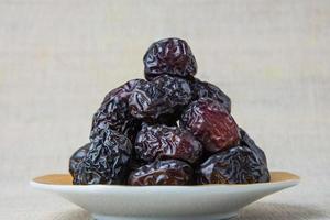 Delicious ajwa dates kurma nabi, or sweet dried dates on a plate, with some falling from the plate, as a meal for breaking the fast, ramadan kareem, empty space, copy space. photo