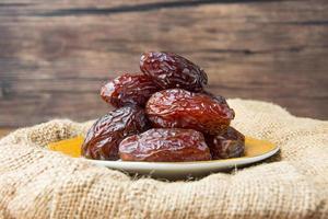 Delicious medjool dates or sweet dried dates on a plate, with some falling from the plate, as a meal for breaking the fast, ramadan kareem, empty space, copy space photo