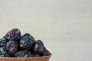 Delicious ajwa dates kurma nabi, or sweet dried dates on a plate, with some falling from the plate, as a meal for breaking the fast, ramadan kareem, empty space, copy space. photo