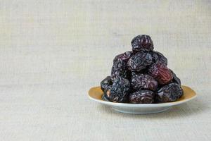 Delicious ajwa dates kurma nabi, or sweet dried dates on a plate, with some falling from the plate, as a meal for breaking the fast, ramadan kareem, empty space, copy space. photo