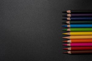 Set of colored pencils, row of wooden colored pencils on black background. colored pencils for drawing. pencils arranged in rainbow colors, colorful, copy space. photo