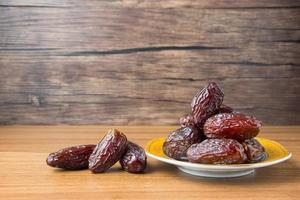Delicious medjool dates or sweet dried dates on a plate, with some falling from the plate, as a meal for breaking the fast, ramadan kareem, empty space, copy space photo