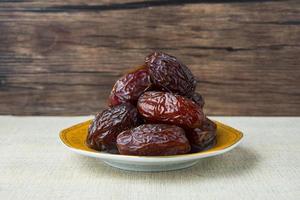 Delicious medjool dates or sweet dried dates on a plate, with some falling from the plate, as a meal for breaking the fast, ramadan kareem, empty space, copy space photo