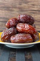 Delicious medjool dates kurma or sweet dried dates on a plate, with some falling from the plate, as a meal for breaking the fast, ramadan kareem, empty space, copy space.