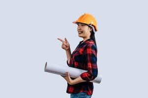 Young female engineer wearing a yellow safety helmet with Blueprints photo