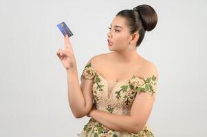 joven novia asiática hermosa publicando con tarjeta de crédito y cepillo de belleza en la mano foto