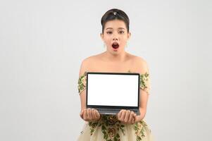 Young asian beautiful bride pose with mock up laptop computer in hand photo